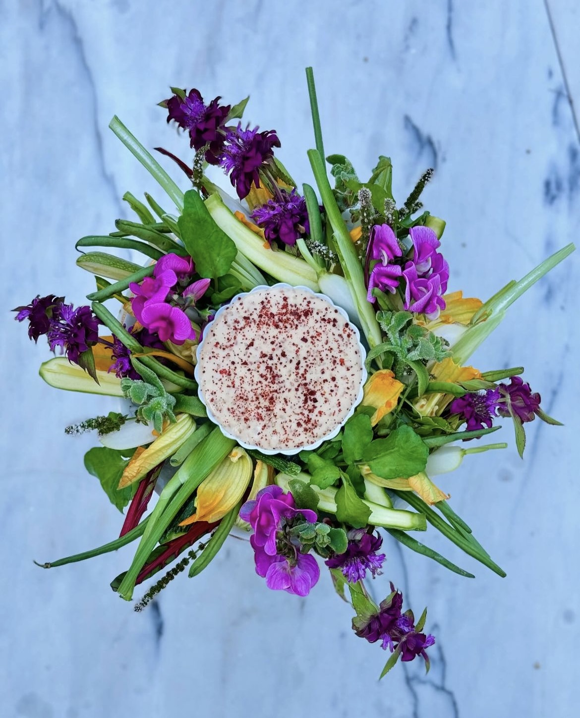 Grøntsager og blomster omkring en dip